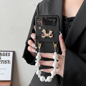 Z Flip 6/7 phone case with metallic bow and elegant pearl hand strap on black leather