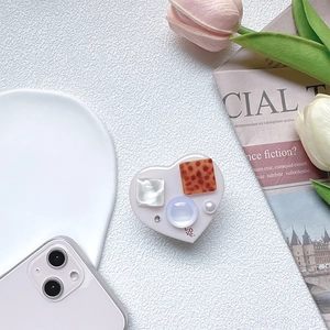 Detail of heart-shaped phone grip with collage texture, faux pearls, and LOVE print