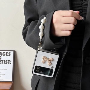 Detail of white leather Z Flip phone case with pearl wrist strap and golden bow
