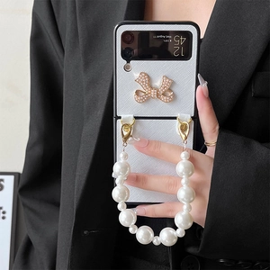 Detail of white leather Z Flip case with pearl bow and luxury pearl handheld chain