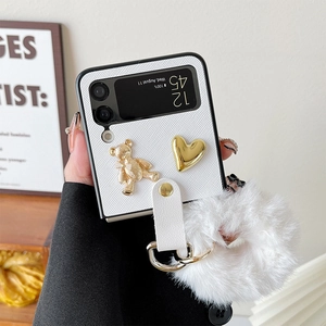 Detail of Z Flip case with golden teddy bear, heart charms and white plush ball ornament
