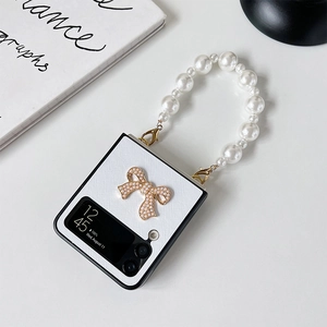 Detail of white textured Z Flip case with golden metal bow and pearl handle chain