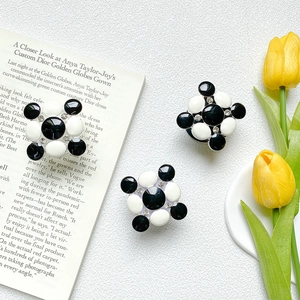 Macro shot of geometric black and white enamel phone grip with rhinestones on stone background