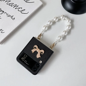 Detail of Galaxy Z Flip case with pearl handle strap and sparkling metal bow ornament