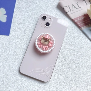 Close-up of cute 3D brown bear pop socket with pink bow and pearls on phone case
