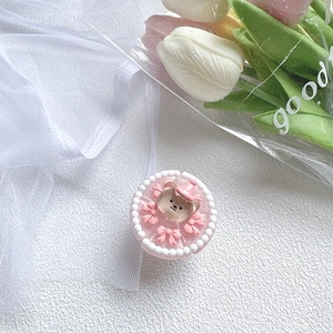 Detail of pink 3D bear phone grip with pearl border and cute ribbons on white texture