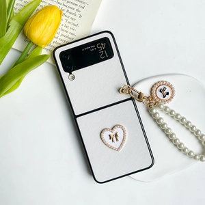 Samsung Galaxy Z Flip case with pearl strap, white heart, and golden bow accent