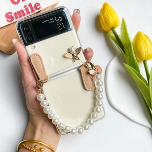Detail of Galaxy Z Flip 6 clear case with pearl bee ornament and elegant hand strap