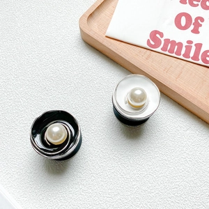 Detail of luxury metal flower phone grips with pearls and enamel finish in black and white