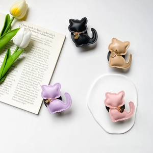 Detailed view of leather cat-shaped phone grips with gold chain charms in four colors