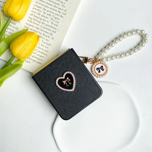Detail of black crosshatch leather case with pearl heart and beaded wrist strap