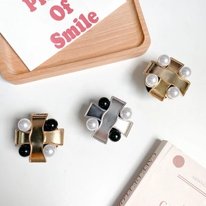Detailed view of wave-shaped metal phone grips with black and white inlaid pearls