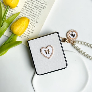 Detail of white textured ZFlip case with pearl strap and gold bow heart ornament