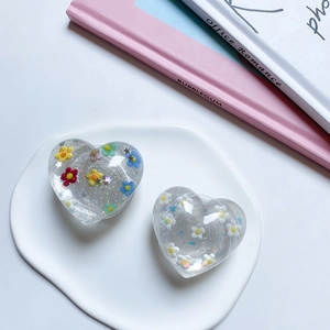 Close-up of heart-shaped phone grips with colorful flowers and silver glitter details