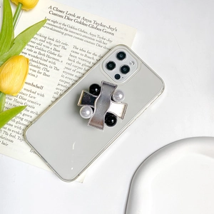 Detail of transparent phone case with metallic cross and faux pearl accents on tulip background