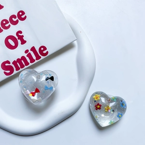 Close-up of transparent heart phone grips with colorful bow, flowers and glitter details