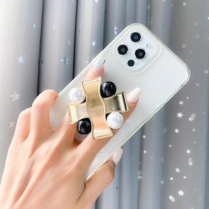Detail of a gold leather cross phone stand with black and white pearl accents