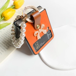Détail de la coque en cuir orange Galaxy Z Flip6 avec bracelet perle et nœud décoratif