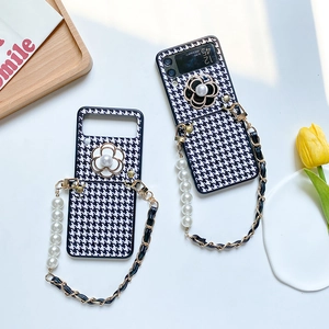 Detail of houndstooth Z Flip case with pearl strap, camellia flower and chain lanyard