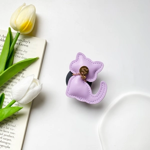 Detail of purple leather cat phone grip with Lucky gold pendant and neat stitching
