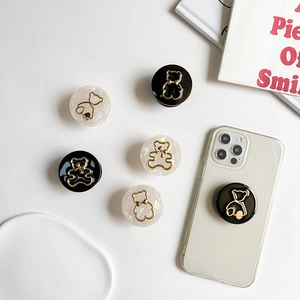 Minimalistische Handy-Halterung mit Marmormuster und goldenem Metallbären auf Smartphone