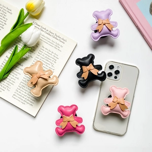 Close-up of bear-shaped expanding phone grips with bow ties and quilted leather texture