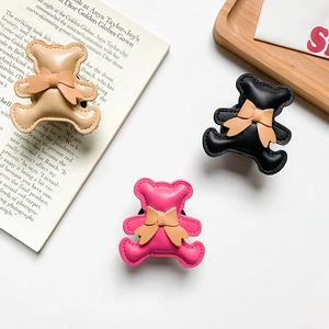 Close-up of cute bear phone grips with leather bows in khaki, black, and rose red colors
