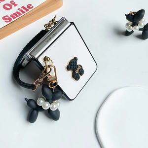 Detail der weißen Lederhülle für Samsung Z Flip mit Bärenplakette und Ballonhund-Anhänger