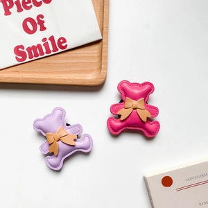 Close-up of cute purple and rose red bear phone grips with bow ties on a tray