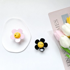 Detail of pink and black sun flower phone sockets with smiles on a white tray