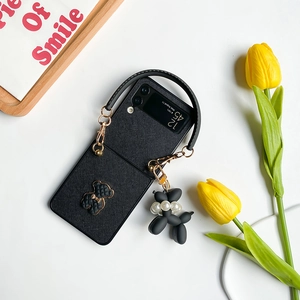 Detail der Galaxy Z Flip 4 Lederhülle in Schwarz mit Bärenlogo und Ballonhund-Anhänger