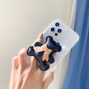 Detail of 3D bear phone grip with pink bow and leather texture on a white smartphone