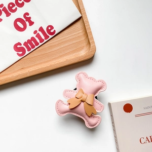 Detailed view of pink leather bear phone grip with bowknot and fine stitching on white desk