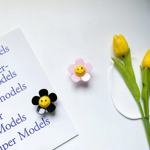 Close-up of pink and black flower phone grip with smiley face on white tray