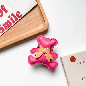 Detailed view of magenta faux leather bear phone holder with a brown bow and stitching