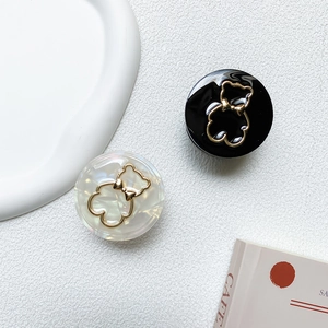 Detail von runden Handy-Halterungen mit luxuriösen Goldbär-Emblemen in Schwarz und Perlweiß