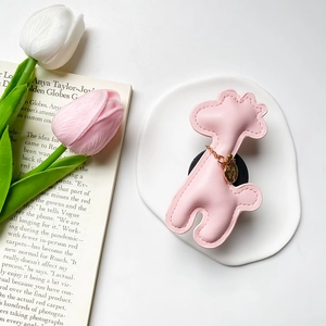 Detail of pink leather giraffe phone grip with gold heart charm and fine stitching
