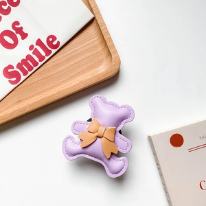 Detail of a purple leather bear phone socket with a brown bow on a wooden tray