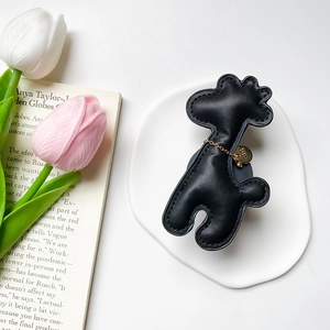 Macro detail of giraffe phone socket in black lychee leather with gold chain decoration