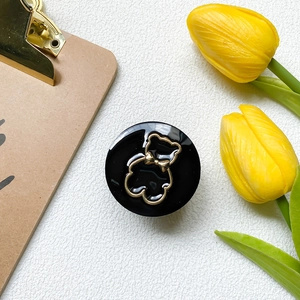 Detailansicht eines schwarzen runden Handyhalters mit luxuriösem Goldbären und Tulpen-Deko