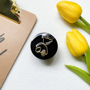 Draufsicht auf einen glänzenden schwarzen Handyhalter mit goldenem Bär und Tulpendeko