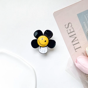 Close-up of minimalist black and white flower phone grip with a yellow smiley face