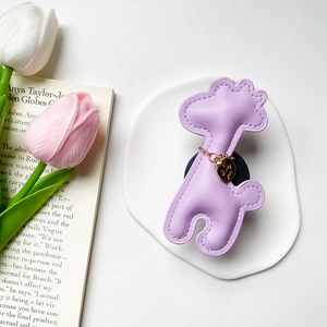 Detail of a purple leather giraffe phone grip with gold charm on a ceramic tray