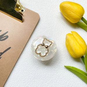 Nahaufnahme eines Handy-Halters mit Marmortextur, Goldbär-Motiv und Tulpen-Dekor