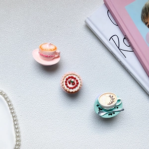 Detailed view of coffee and strawberry cake miniature phone grips on a stylish desk set