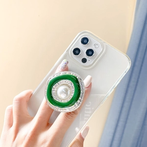 Detail of vintage phone grip featuring large pearl and green enamel on a clear case