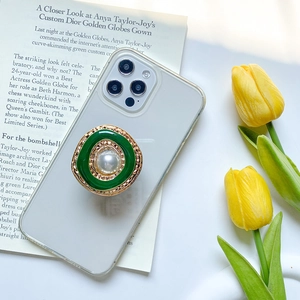 Vintage gold metal phone socket with green enamel and large pearl on a clear case