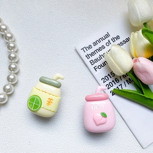 Close-up of cute milk bottle phone grips with 3D lime and peach silicone charms