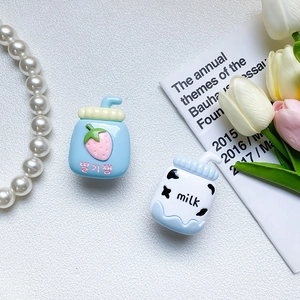 Detail of cute milk bottle phone grip resin accessories with strawberry and cow patterns