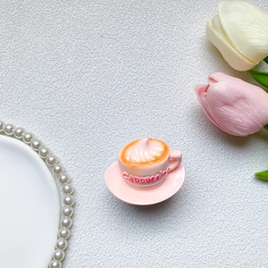 Detailed view of a pink miniature cappuccino cup resin phone grip on a white surface